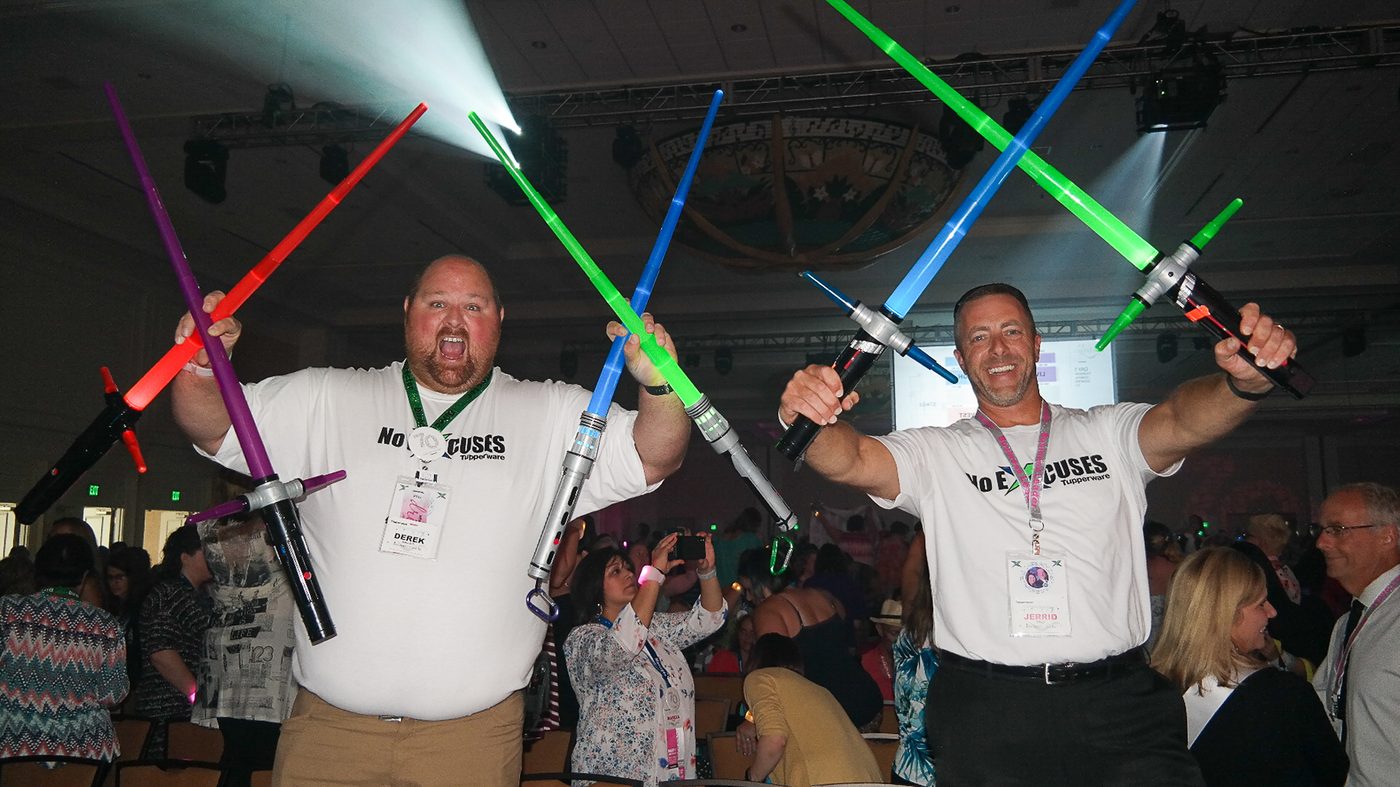Two guests holding up glowing toy sabres in a ballroom