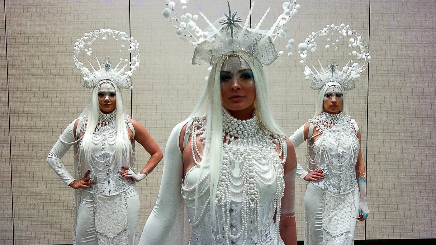 Three costumed performers in white with crystal headpieces
